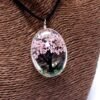 Närbild på halsband med rosa blommor och trädmotiv