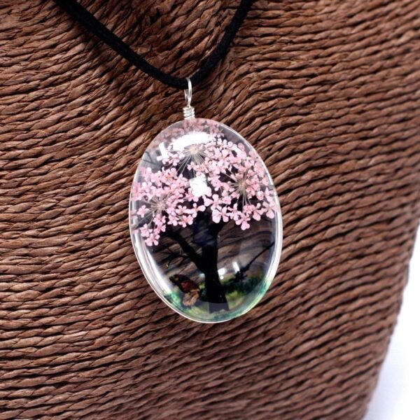 Närbild på halsband med rosa blommor och trädmotiv