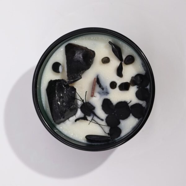Närbild på doftljus med svart obsidian och torkade blommor